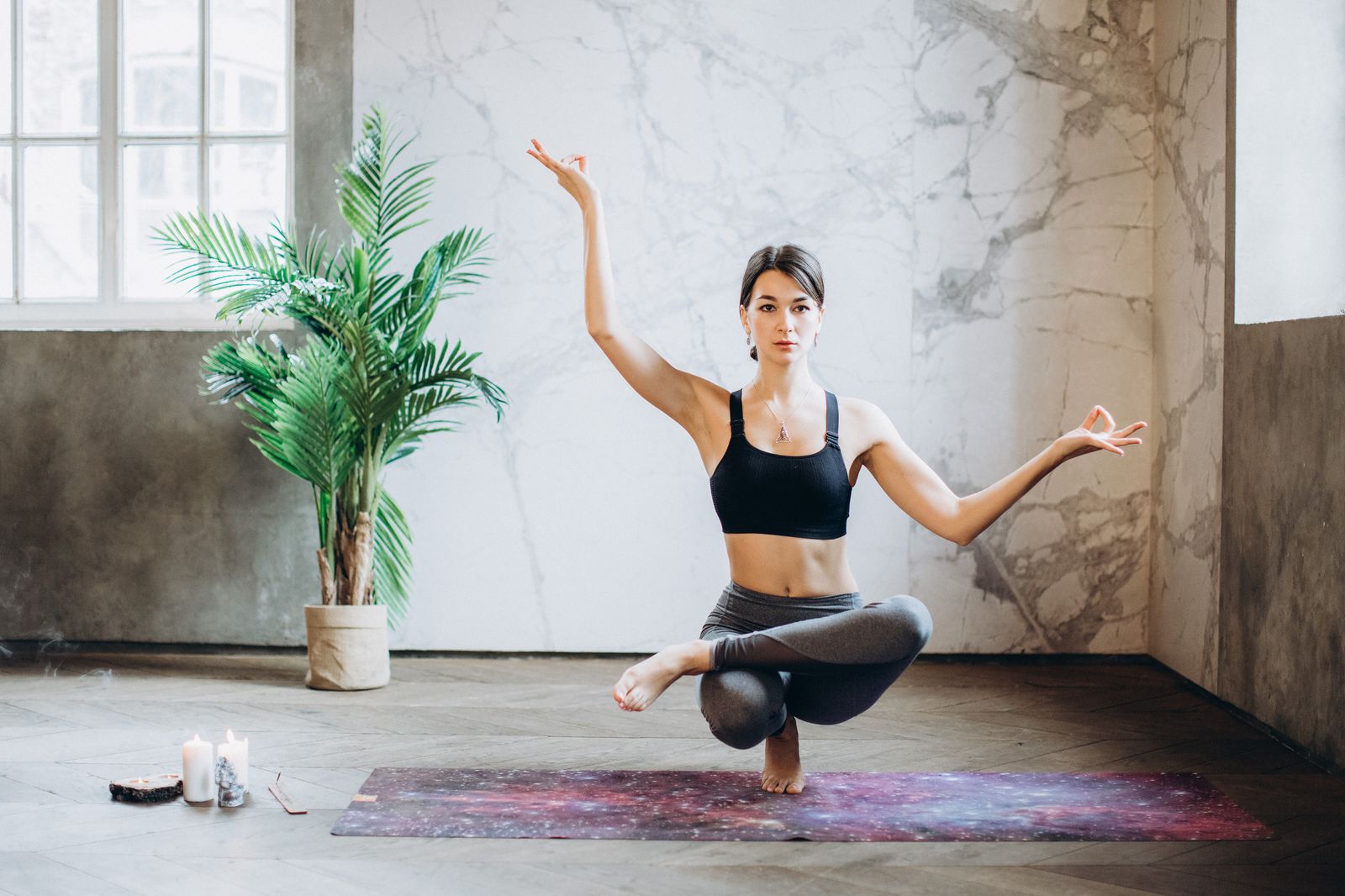 Postura de yoga sobre esterilla junto a una planta